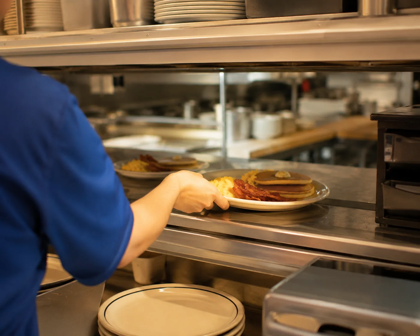 Diner kitchen pass-through with a server picking up an order, related to IHOP careers and jobs