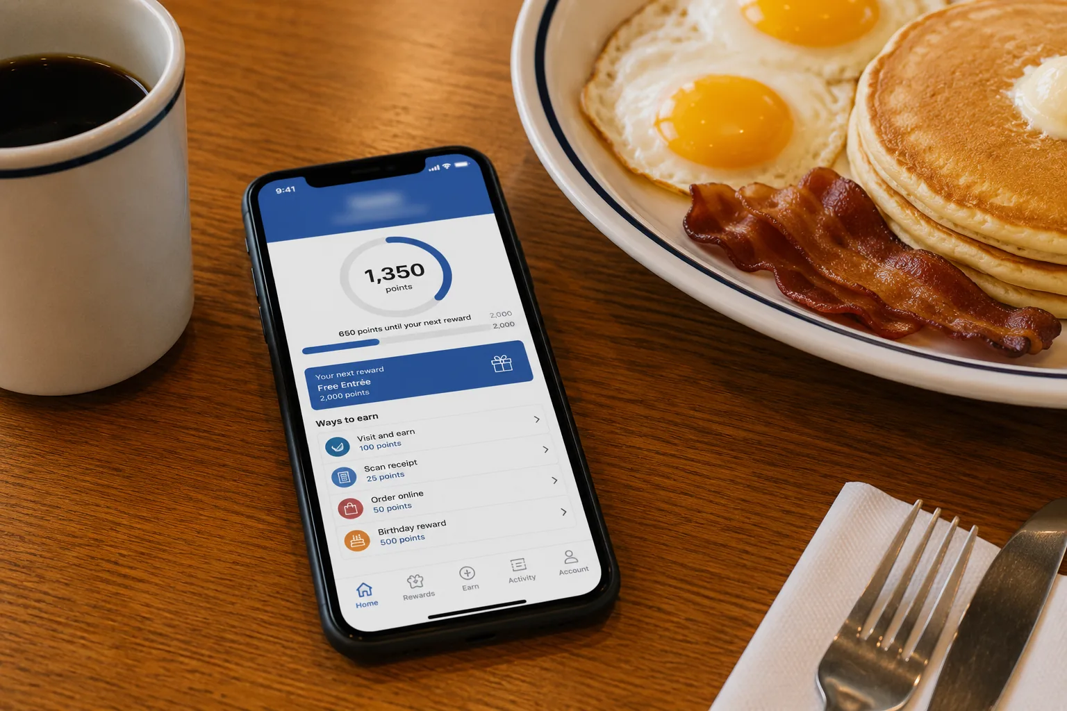 Phone showing a rewards app at a diner table, related to IHOP deals and coupons