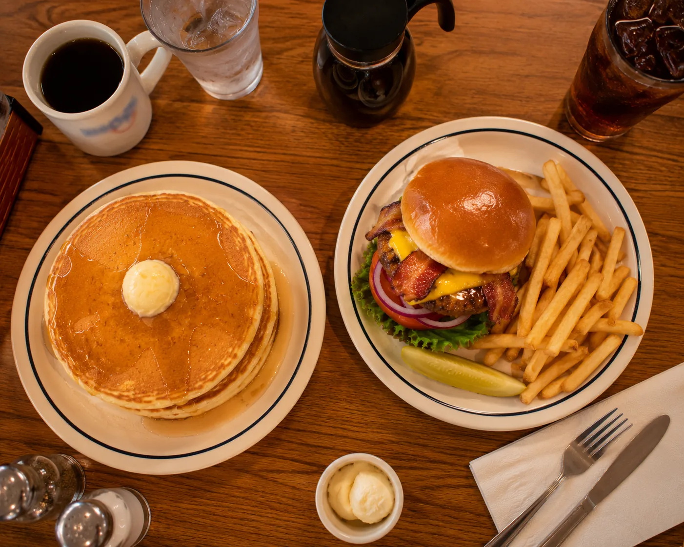 Table with both pancakes and a burger plate, showing IHOP's all-day breakfast alongside lunch and dinner